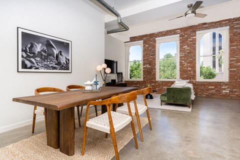a dining room with a wooden table and chairs and a living room with exposed brick at Imperial Hardware Lofts, California