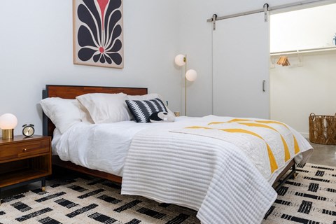 a bedroom with a bed with white sheets and a yellow and black blanket at Imperial Hardware Lofts, California