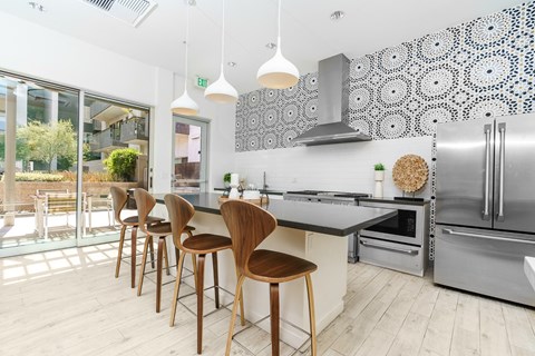 a kitchen with a island and bar stools and a stainless steel refrigerator