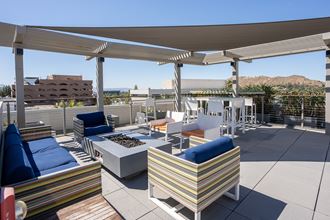 a rooftop patio with couches and chairs and a fire pit