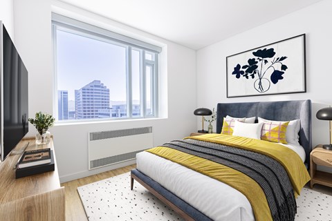 A modern bedroom with a large bed and a city view through the window.