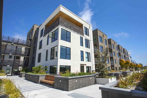 A modern apartment building with a courtyard in front.