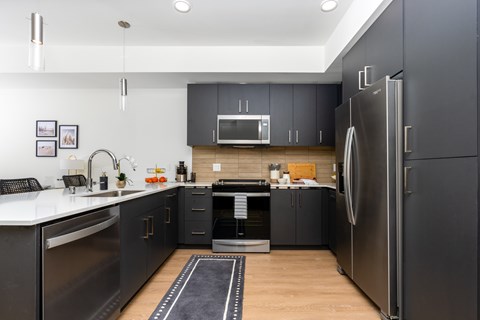 A modern kitchen with dark grey cabinets and stainless steel appliances.
