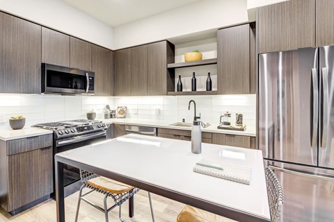 A modern kitchen with a stainless steel refrigerator and a white island counter.