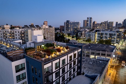 an aerial view of a city skyline at night with buildings and a rooftop terrace