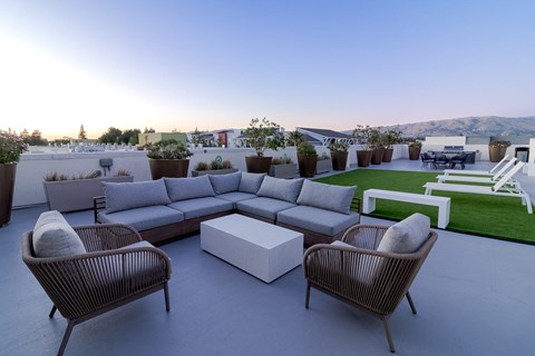 a lounge area on the roof of a building with couches and chairs