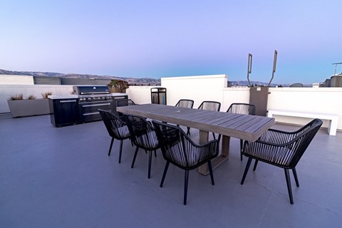 a patio with a wooden table and chairs and a grill