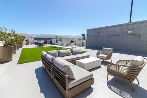 a lounge area on the roof of a building with couches and chairs
