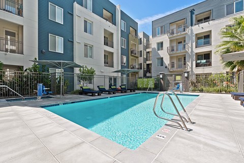 San Jose, CA Apartments - Gated Swimming Pool With Plenty Of Seating And Shade. Linq Apartment Homes Are In The Background.