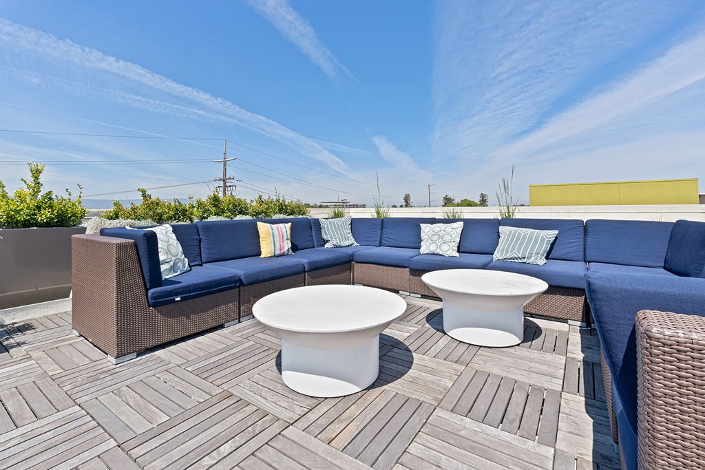 Apartment San Jose, CA - Rooftop Lounge With Outdoor Couches, Tables With Chairs, And Maintained Potted Plants.
