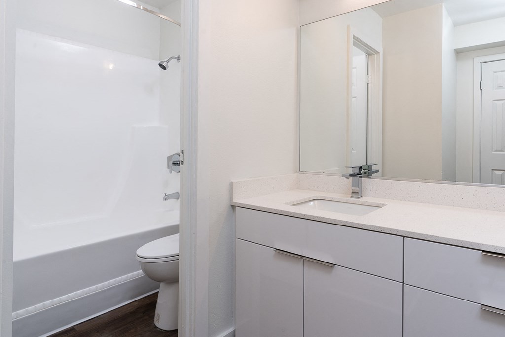 San Diego, CA Apartments - Bathroom Has A Shower With Tub, Toilet, Large Mirror, Sink, And White Cabinets With Large Counter Space.