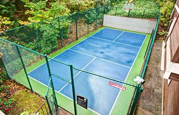 A tennis court surrounded by a green fence. at Lakemont Orchard Apartments, Washington, 98027