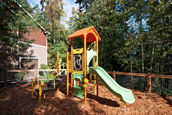 A playground with a green slide and a yellow and orange play structure. at Lakemont Orchard Apartments, Issaquah , Washington