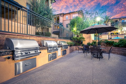 A patio with a table and chairs and a grill.