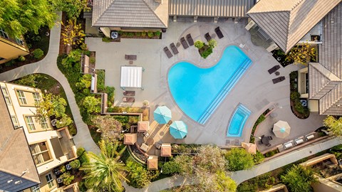 An aerial view of a swimming pool surrounded by a garden and buildings.