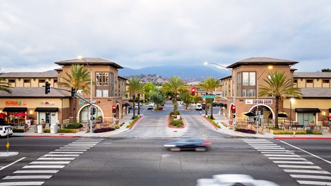 A street view of a town with a car driving down the road.