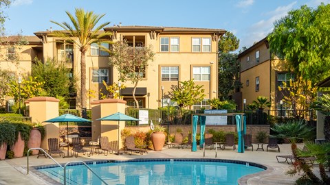 A swimming pool surrounded by a patio with chairs and umbrellas.