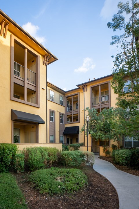 A building with a yellow facade and a balcony on the second floor.