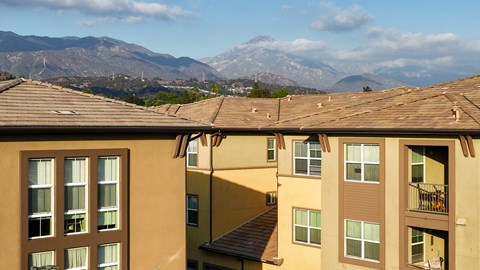Apartment buildings with mountainous background under a blue sky.