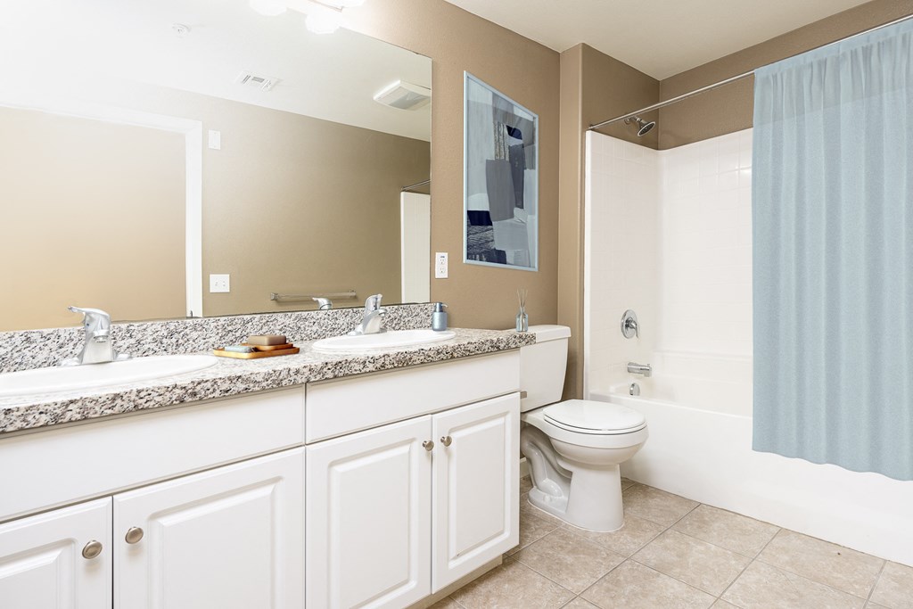 a bathroom with white cabinets and a blue shower curtain