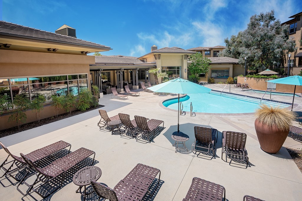 a pool with lounge chairs and umbrellas at the enclave at woodbridge apartments in sugar