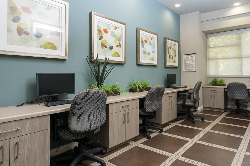 a room with three desks and three computer monitors