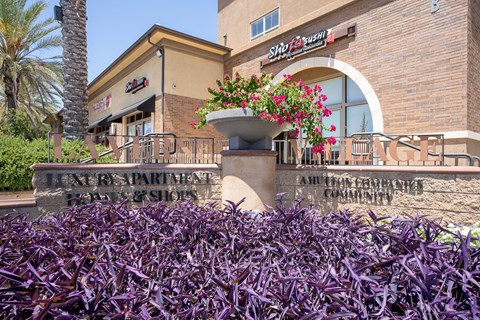 a building with a sign on it and purple plants in front of it