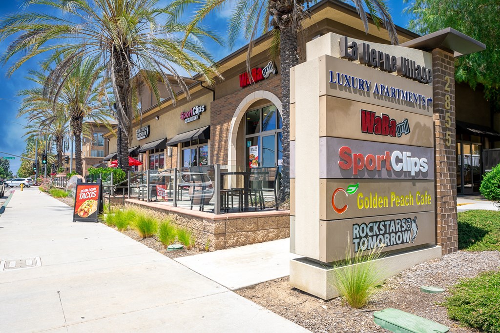 a restaurant exterior with palm trees and a sidewalk in front of it