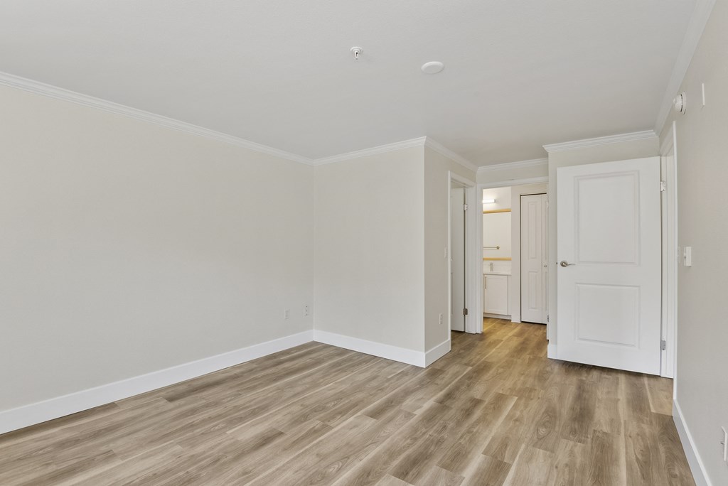 a bedroom with wood style floors and white walls