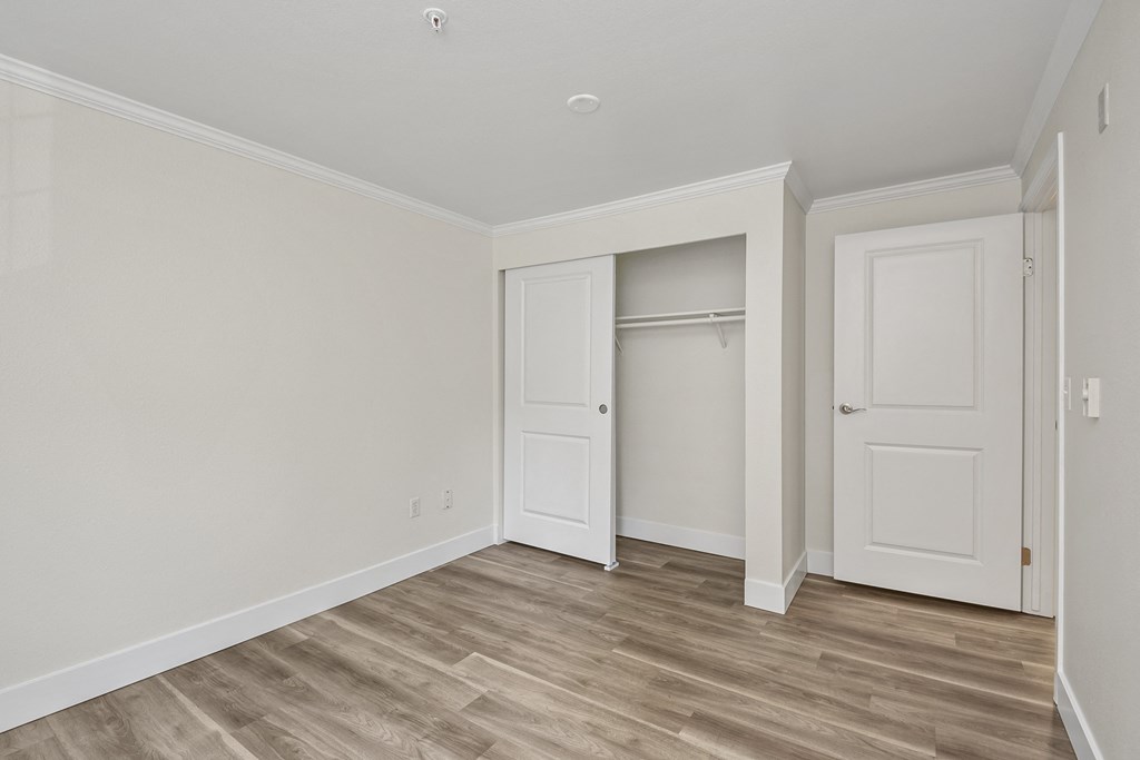 a bedroom with hardwood floors and white walls