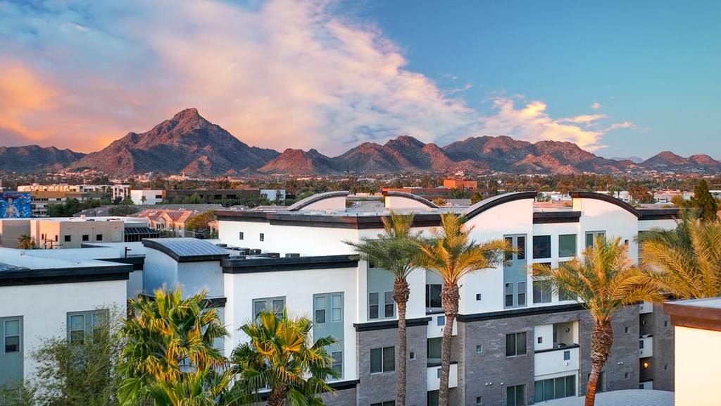 an aerial view of apartments with palm trees and mountains in the background