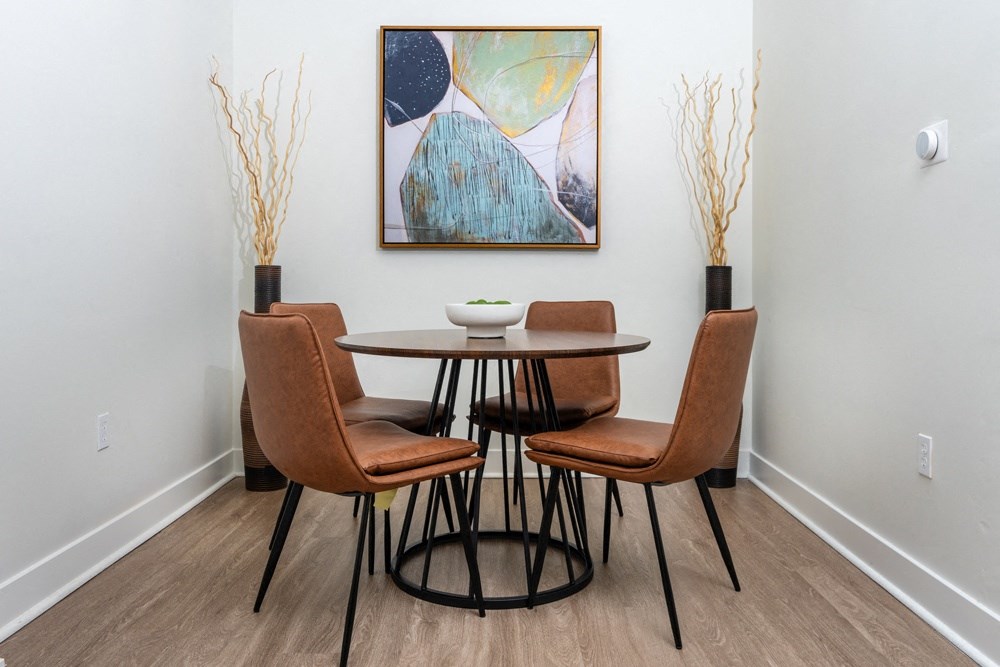 a dining room with a table and chairs and a painting on the wall