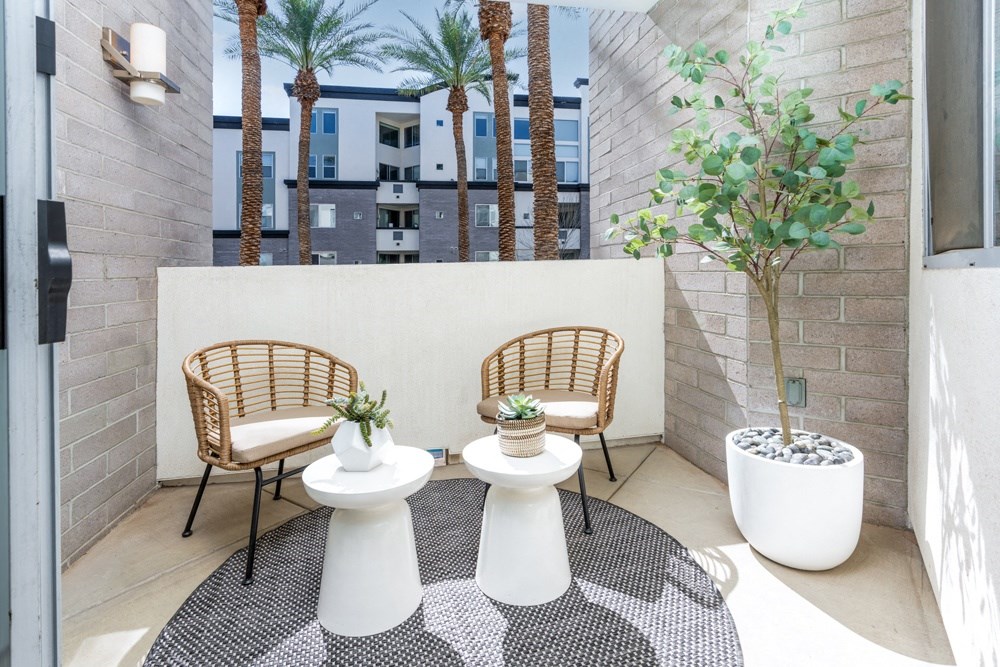 a patio with two chairs and a table with potted plants