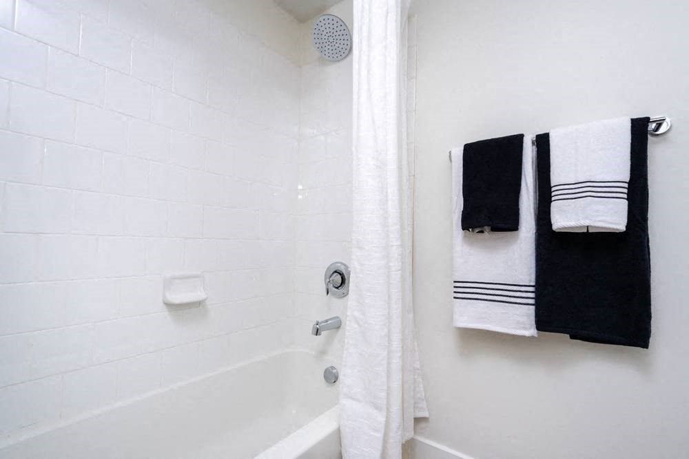 a white bathroom with black and white towels and a tub
