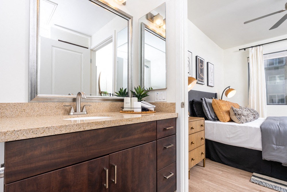 a bathroom with a sink and a mirror and a bedroom with a bed