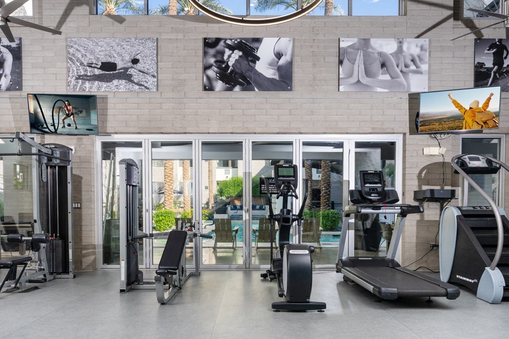 a gym with cardio equipment and pictures on the wall