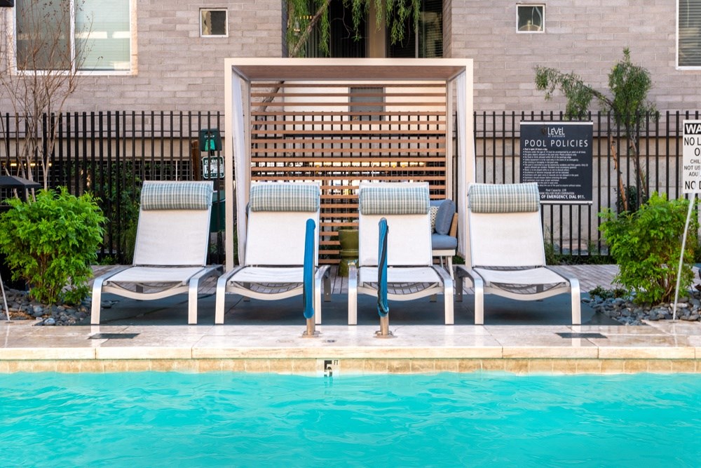 a row of lounge chairs next to a swimming pool