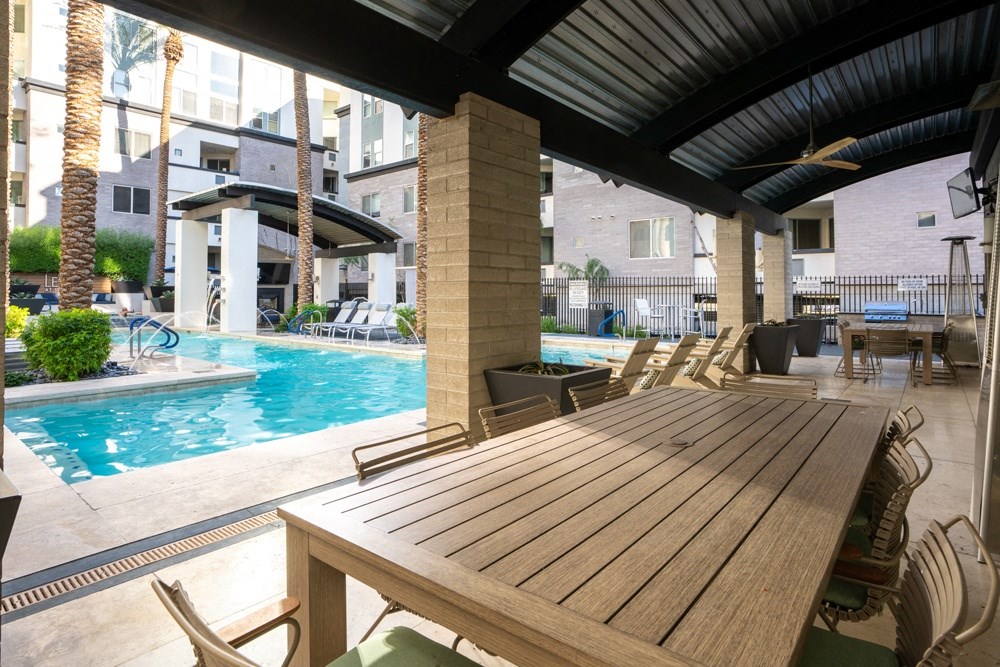 a large wooden table next to a swimming pool