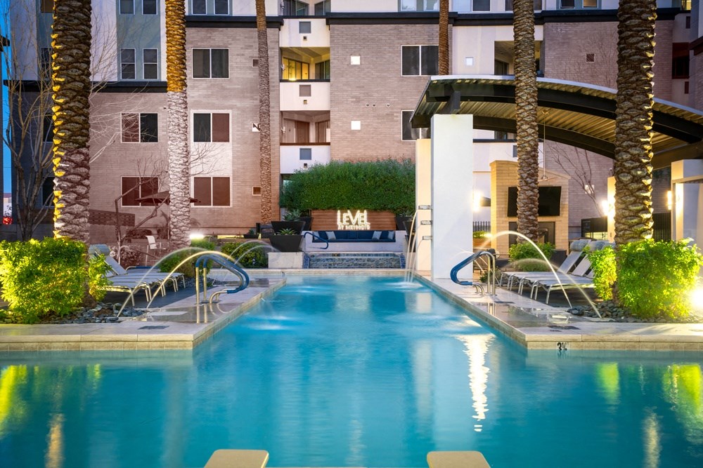 a swimming pool with palm trees and a building in the background