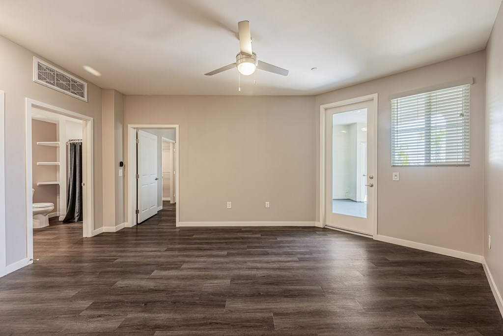 A spacious room with a ceiling fan and hardwood flooring.
