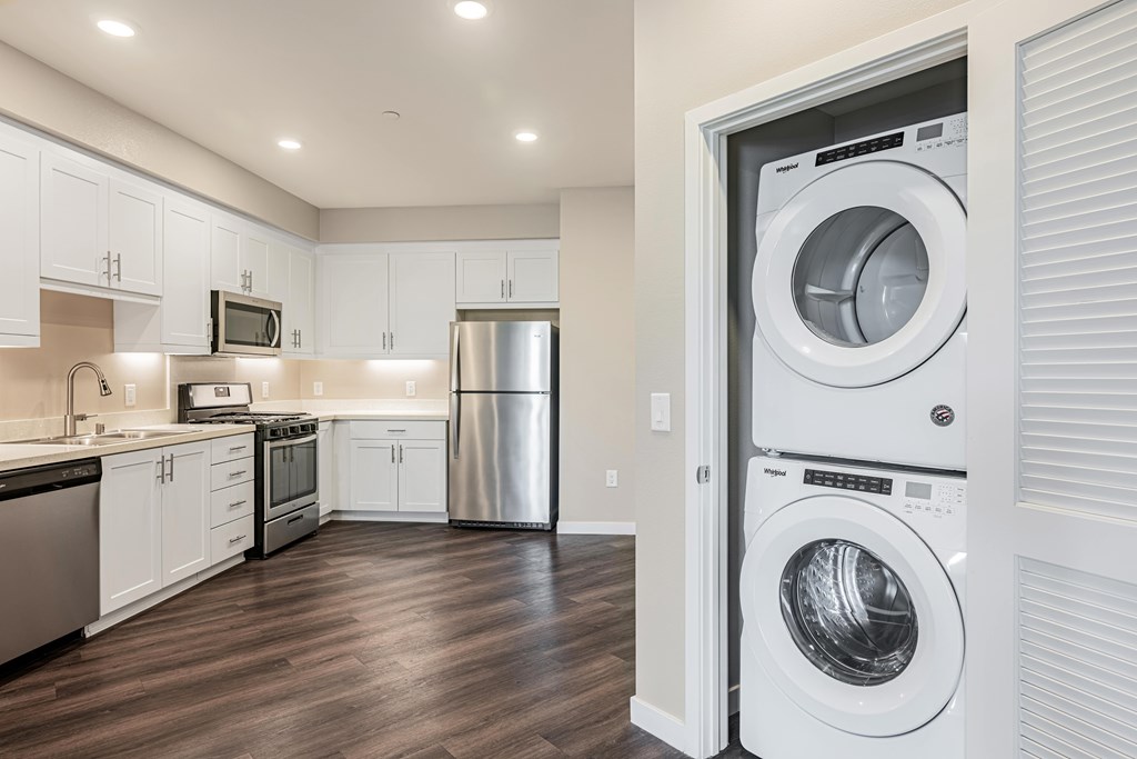 A modern kitchen with a refrigerator, microwave, oven, and washing machine.