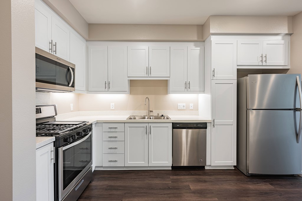 A modern kitchen with white cabinets and stainless steel appliances.