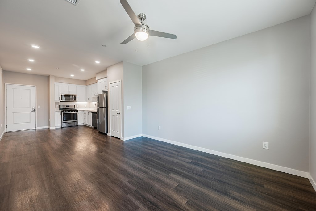 A spacious room with a kitchen area and a ceiling fan.