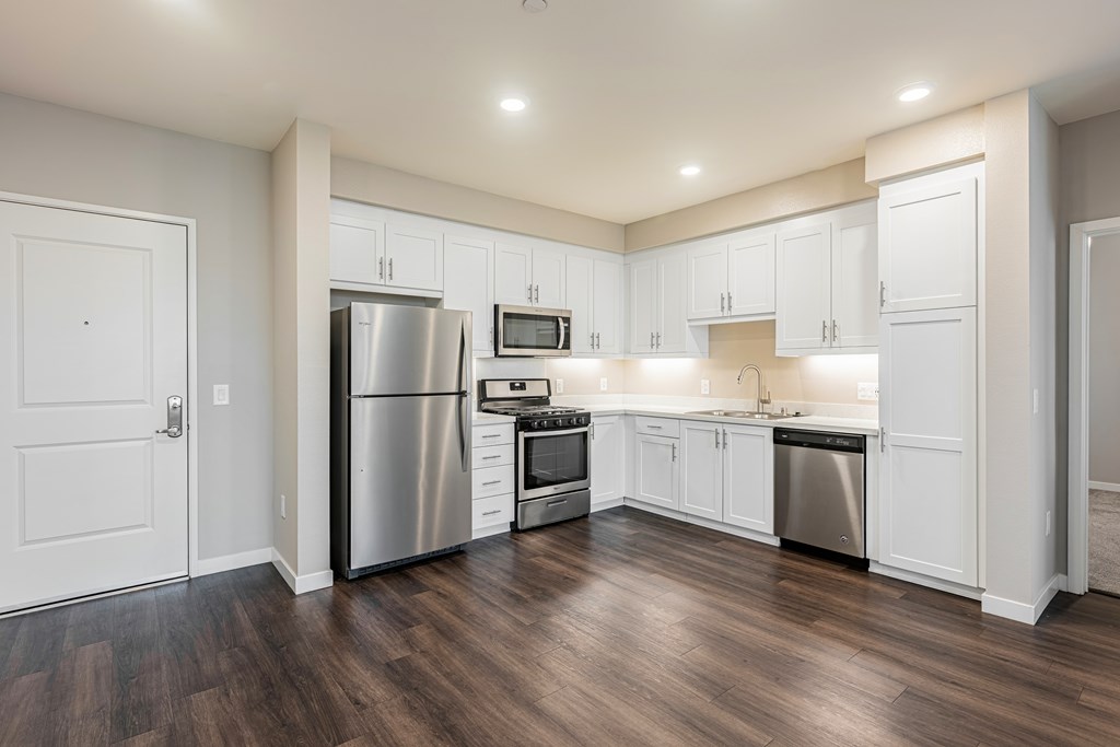 A modern kitchen with white cabinets and stainless steel appliances.