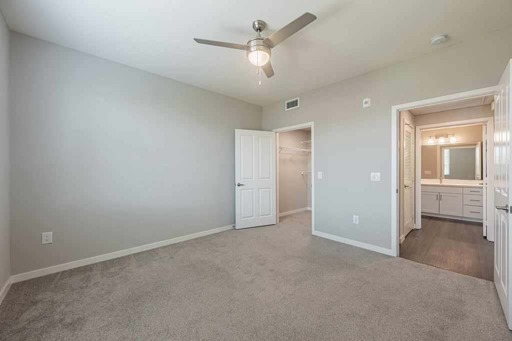 A room with a ceiling fan and carpeted floor.