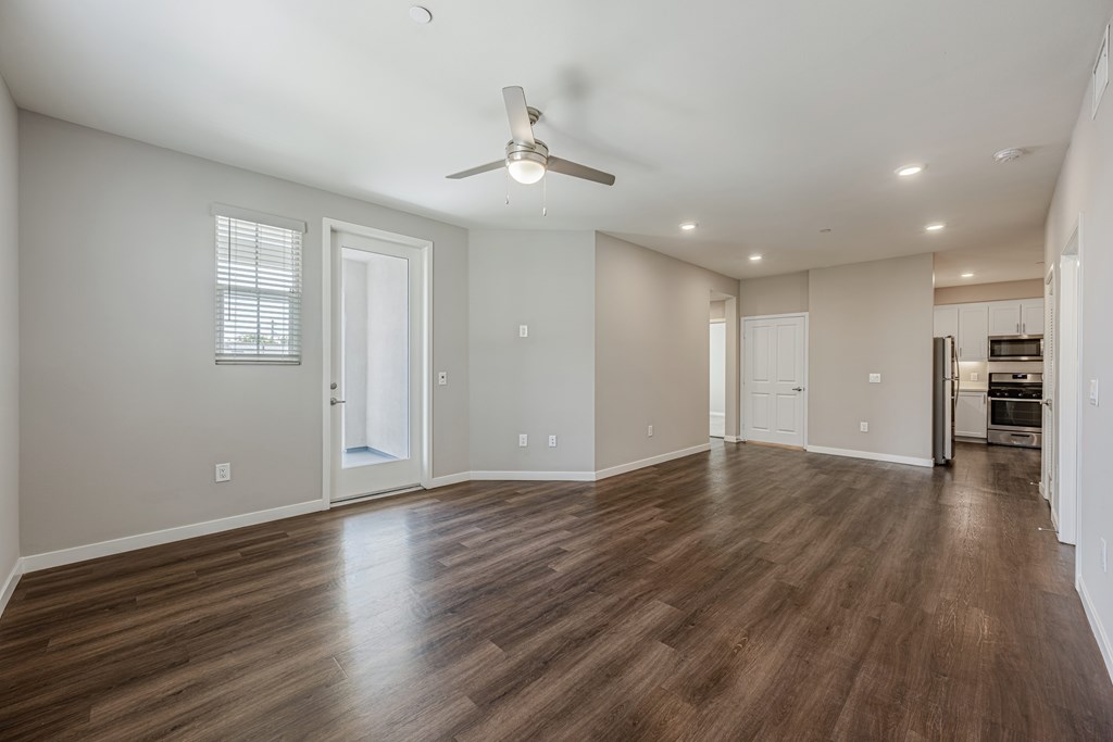 A spacious room with wooden floors and a ceiling fan.