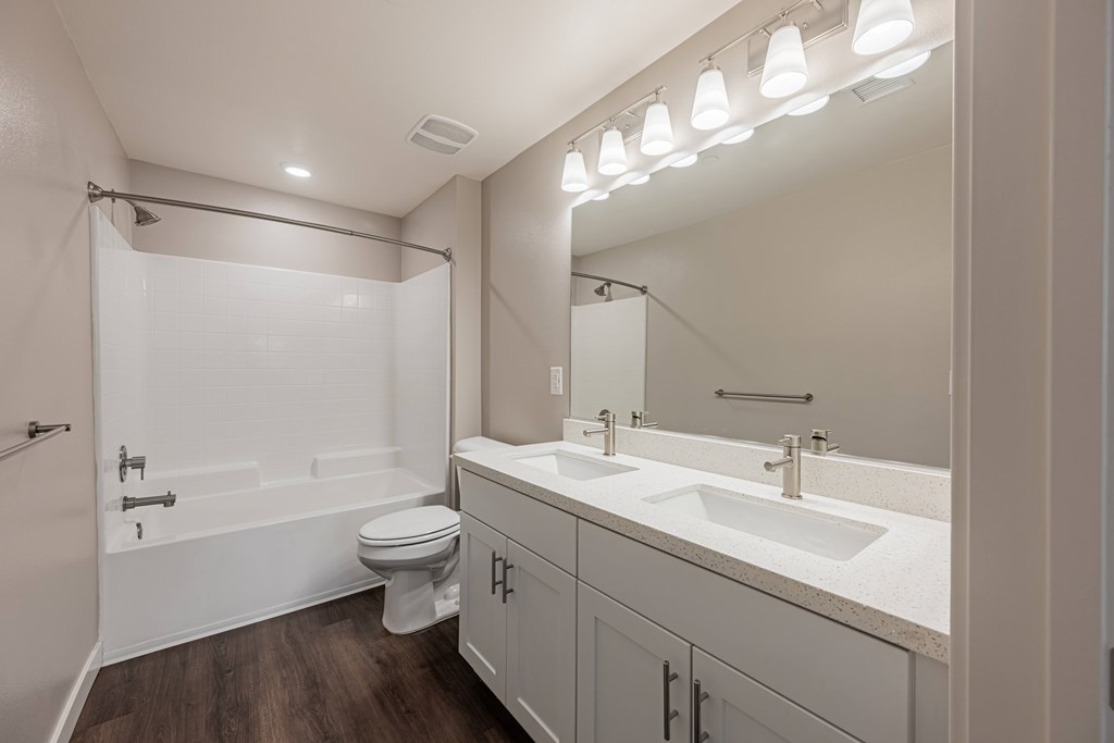 A white bathroom with a toilet, sink, and mirror.