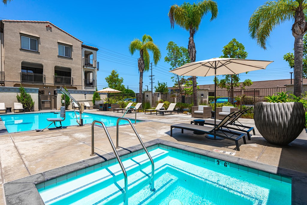 A swimming pool with a sun lounger and umbrella.