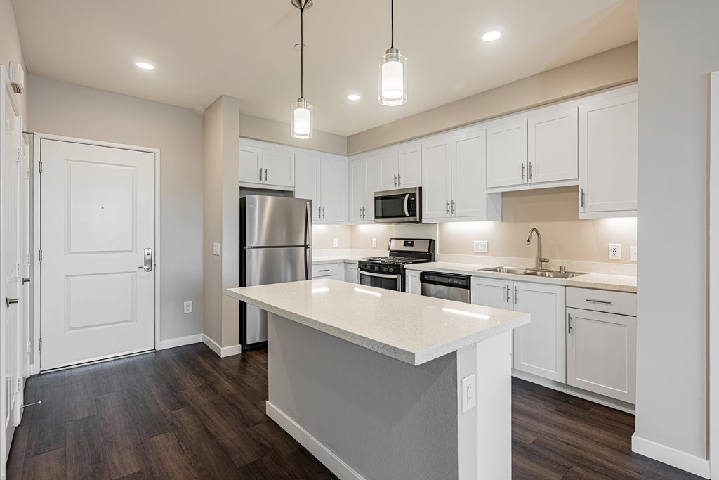 A kitchen with white cabinets and a white island.