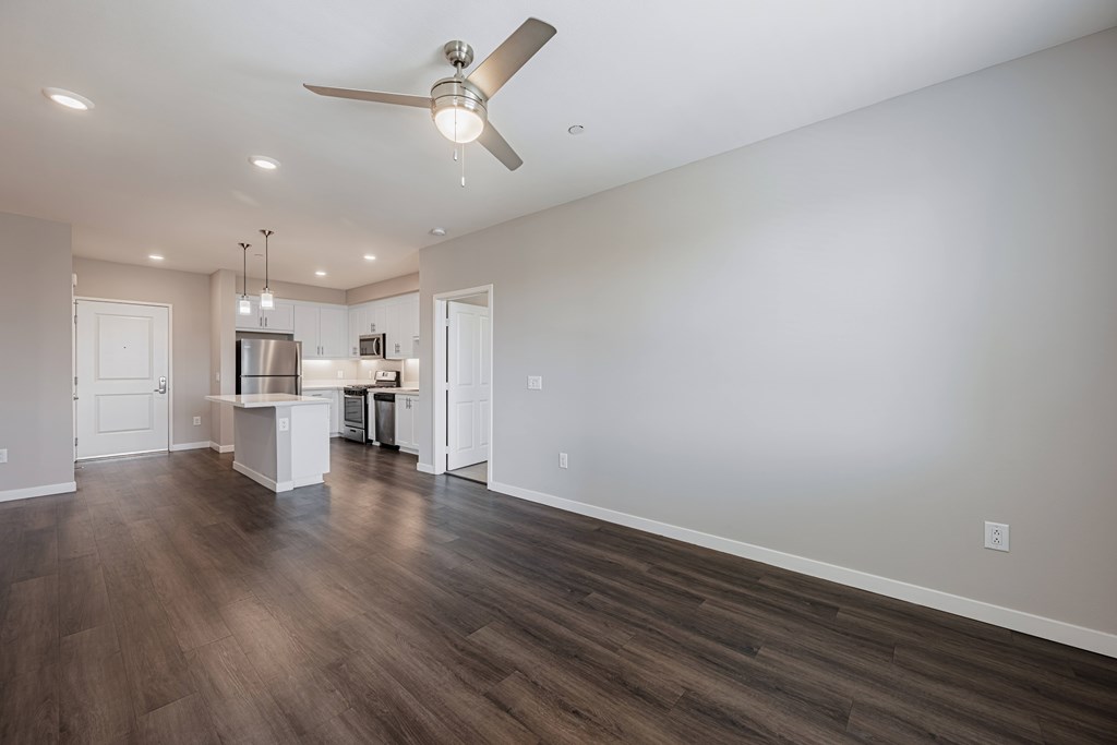 A spacious room with a ceiling fan and wooden flooring.